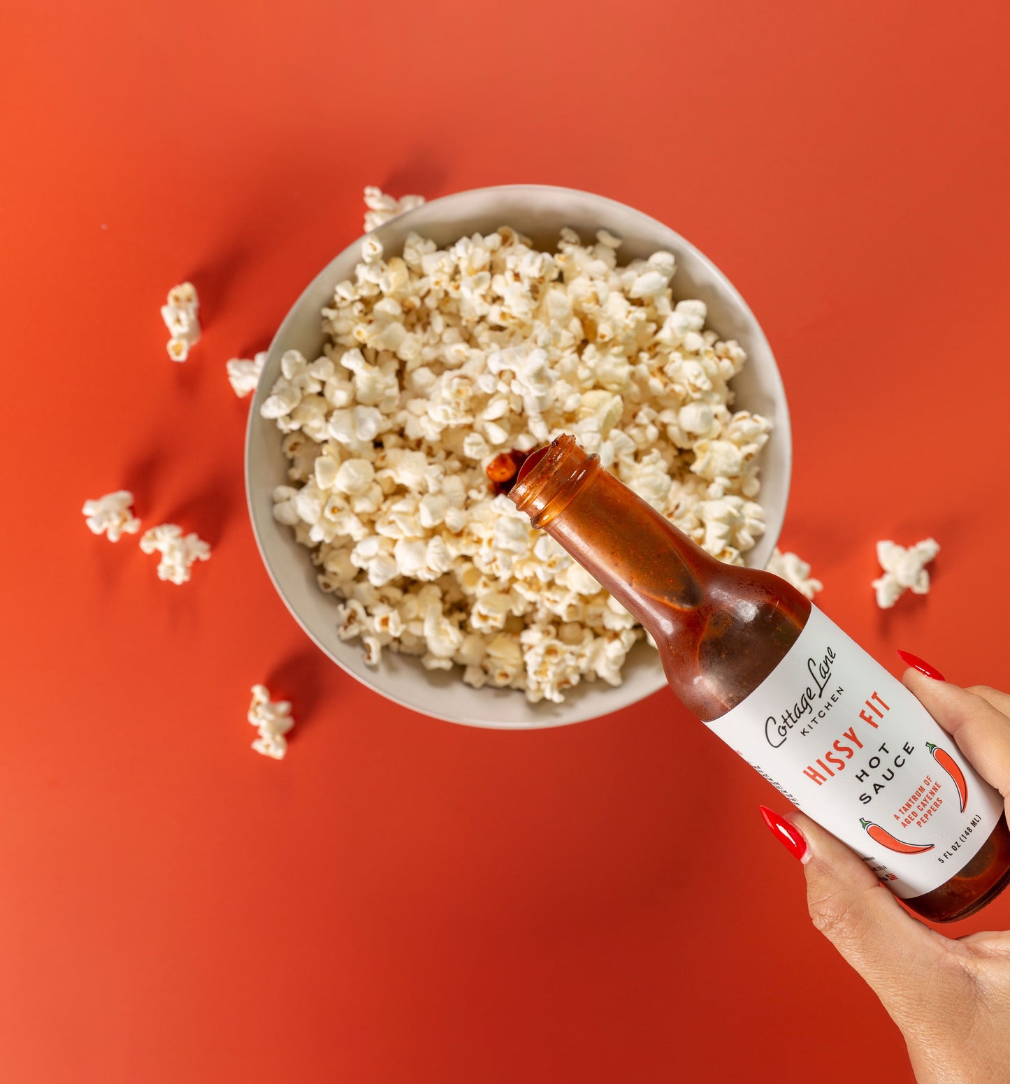 Hissy Fit Hot Sauce being poured on a bowl of Popcorn