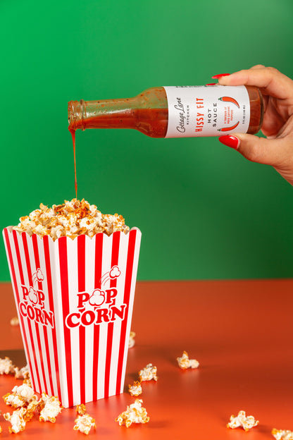 Hissy Fit Hot sauce being poured on a box of popcorn
