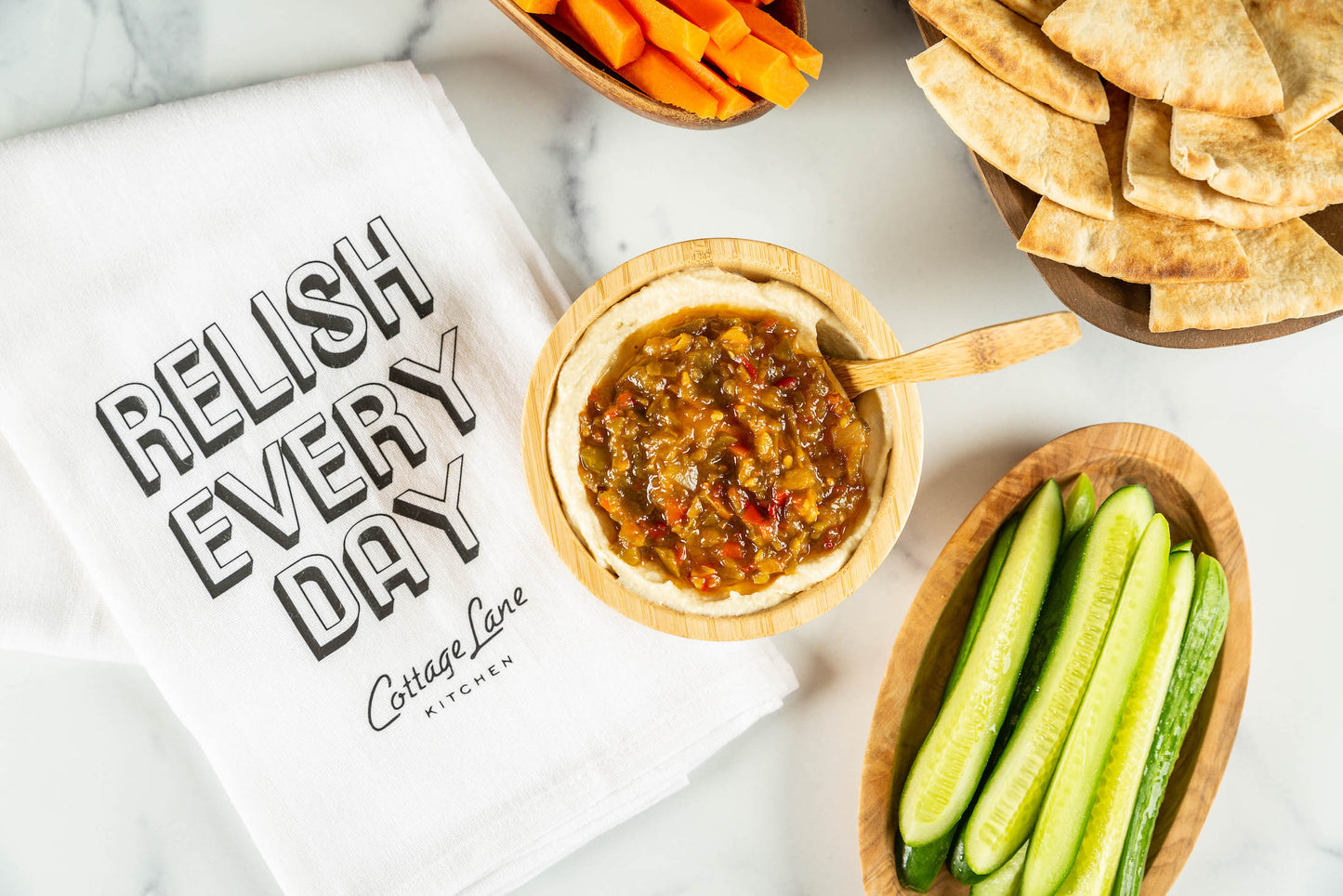 Get Me A Switch Spicy Pepper Relish on Hummus with a dish towel that reads Relish Every Day Cottage Lane Kitchen