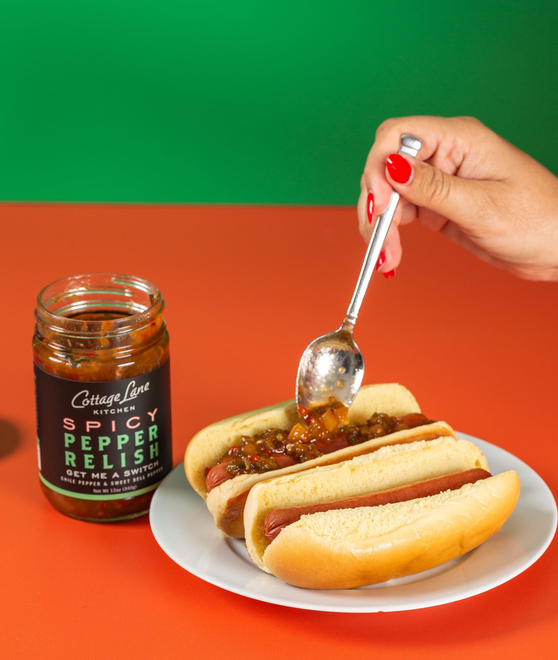 hand putting The Switch Spicy Pepper relish on hotdogs