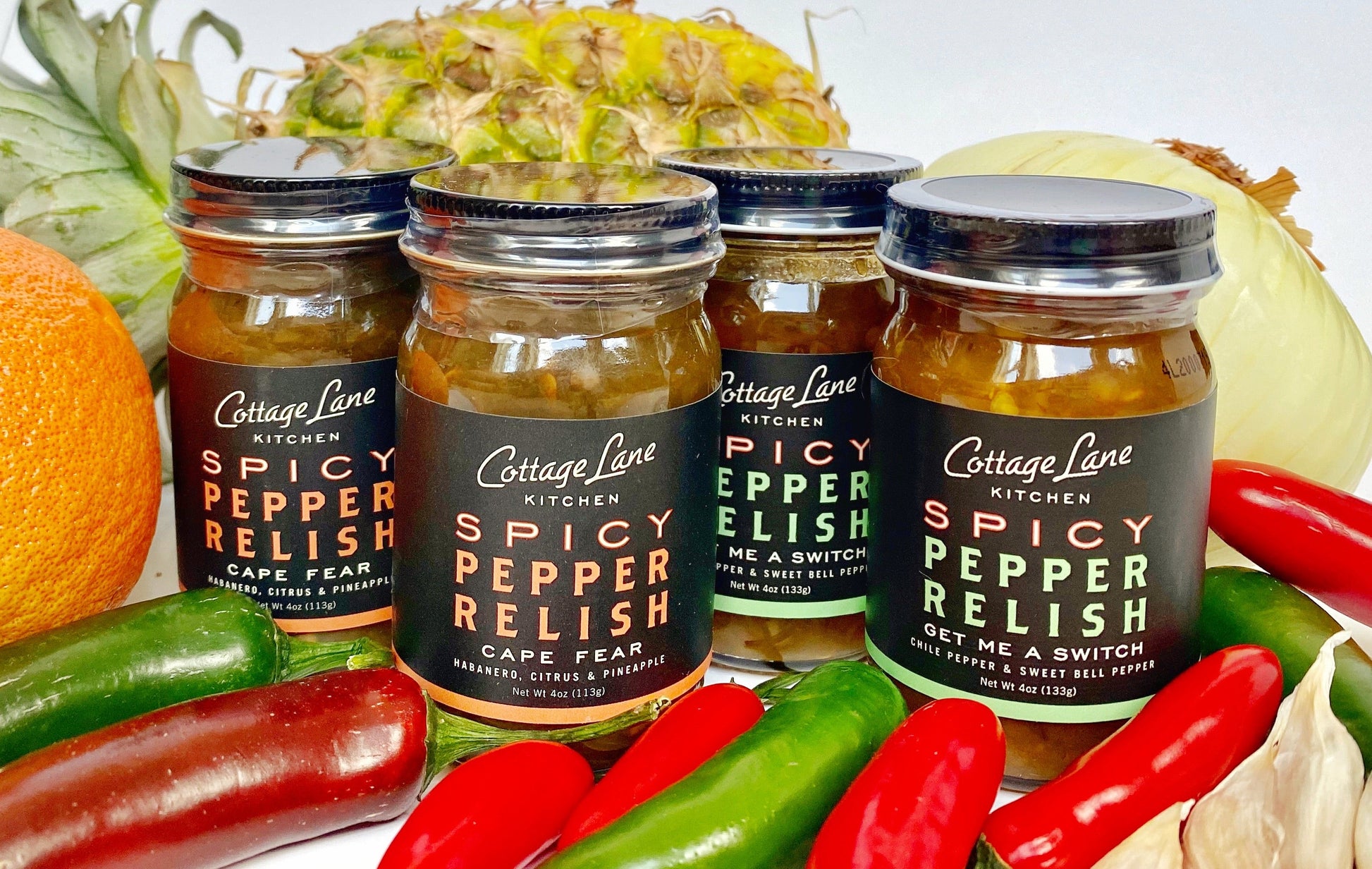 four small bottles of spicy pepper relish by cottage lane kitchen with fresh produce ingredients